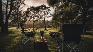Un espace extérieur aménagé avec deux chaises et une table, entouré d’arbres.