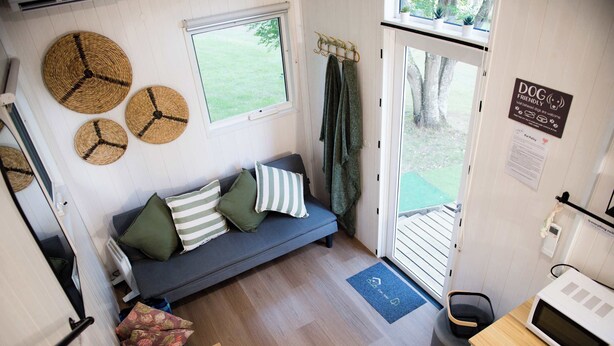 Un espace de vie compact comprenant un canapé, un coin repas, une petite cuisine et une vue sur l’extérieur.