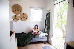 A cozy room with a bed, a window, and three woven wall decorations.