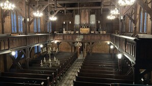 A church interior with wooden pews, a central aisle, and a large organ at the front. - Quiet location, beautiful view, garden, charging station, table football, darts (Mellenbach Glasbach)