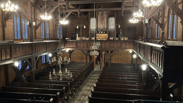 L’intérieur d’une église, avec des bancs en bois, une allée centrale et un grand orgue à l’avant.