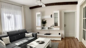 A modern living room with a grey sofa, a white coffee table, and a built-in TV shelf. - Quiet location, beautiful view, garden, charging station, table football, darts (Mellenbach Glasbach)