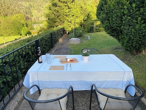 Une table dressée à l’extérieur, avec vue sur une zone boisée.