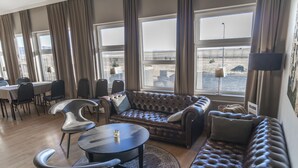 Un salon moderne avec un canapé en cuir, une table basse ronde et un coin repas comprenant des chaises et une table.
