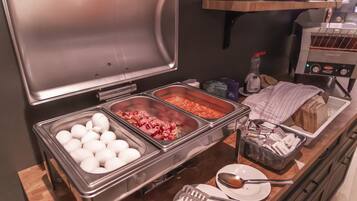 A buffet setup with various food items including eggs, meat, and bread.