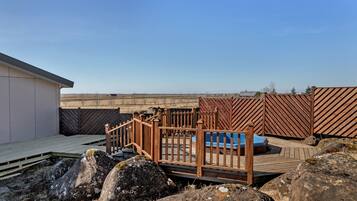 Eine Dachterrasse mit Holzzaun, kleinem Pool und großen Steinen.