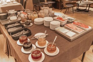 A buffet setup with various food items and condiments on plates and in jars. - Hótel Kvika (Sveitarfélagid Ölfus)