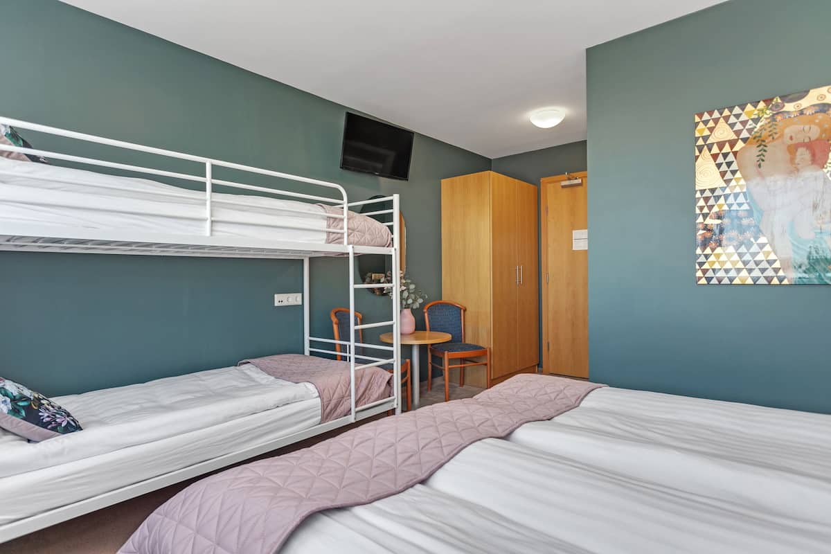 A room with bunk beds, a desk, and a chair.