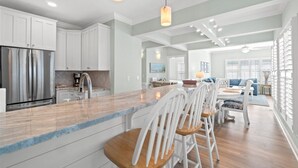 Una cocina amplia con armarios blancos, un refrigerador de acero inoxidable y una isla de madera con taburetes de bar.