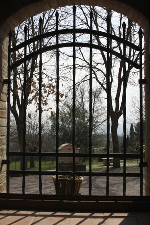 Step through the historic gate into a serene park setting with mature trees and a tranquil atmosphere.