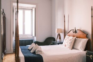 A hotel room with a four-poster bed, a desk with a lamp, a chair, and a window with a view. - Casa Didi - Sintra (Sintra)