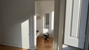 Ένας διάδρομος με ξύλινο δάπεδο, λευκούς τοίχους και μια κρεμαστή κρεμάστρα για παλτό.