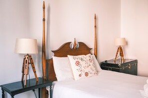 A bed with a wooden headboard, two bedside tables with lamps, and a floral pillow. - Casa Didi - Sintra (Sintra)