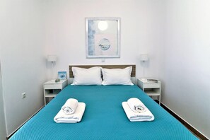 Une chambre d’hôtel avec un lit, deux oreillers blancs, deux tables de chevet avec des lampes, un tableau encadré au mur et deux serviettes sur le lit.