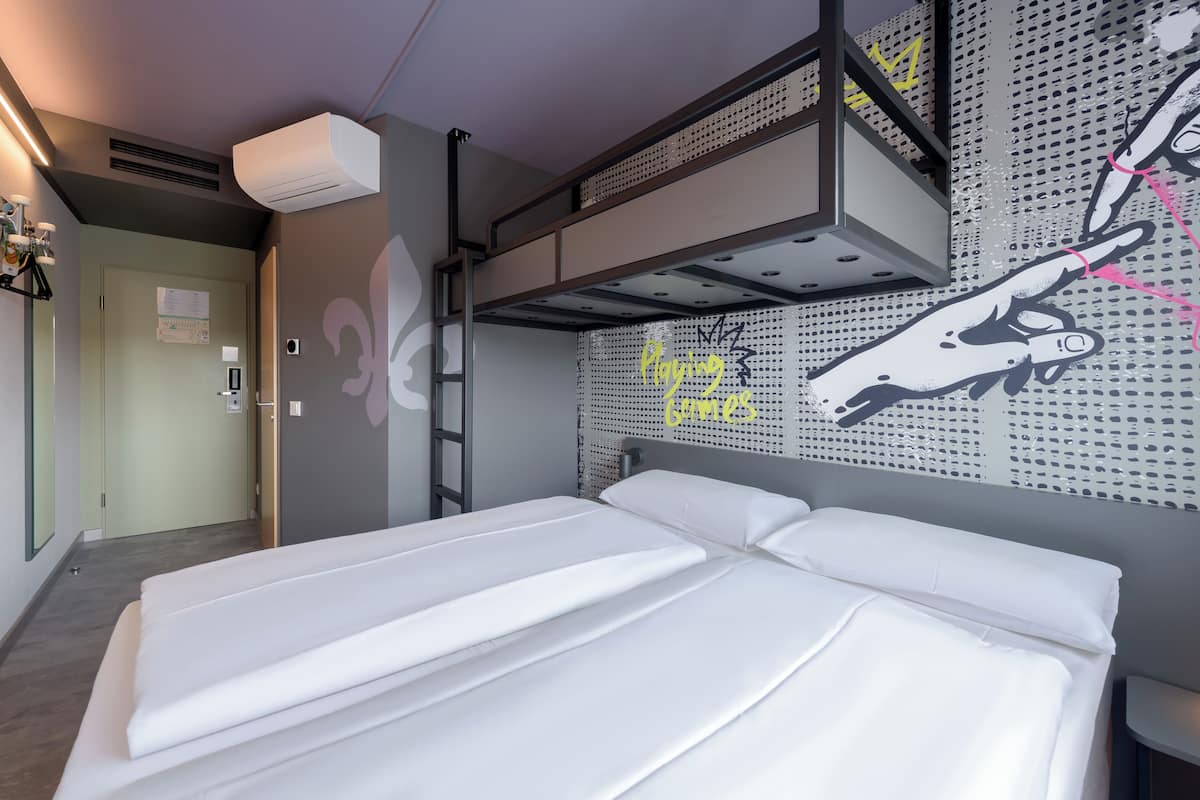 Habitación con literas, un mural en la pared, una escalera y una puerta.