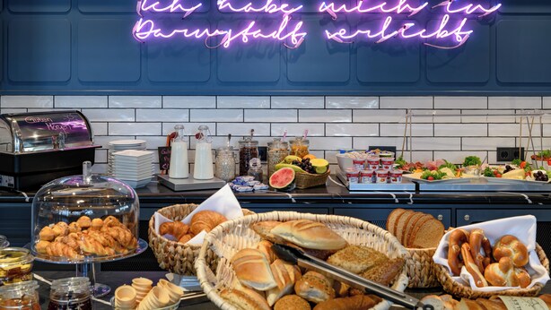A breakfast buffet with various breads, pastries, and fruits. - Felix Hotel Darmstadt (Darmstadt)