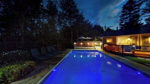 A swimming pool with lounge chairs, a covered deck, and a building with a 'No Lifeguard on Duty' sign. - Room 8 (3rd Floor and Shared Bathroom) (Laconia)