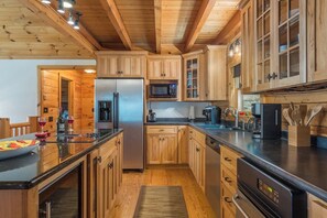 A modern kitchen with wooden cabinets, stainless steel appliances, and a black countertop.