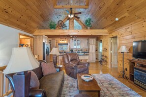 A spacious living room with a high ceiling, a fireplace, and a television.
