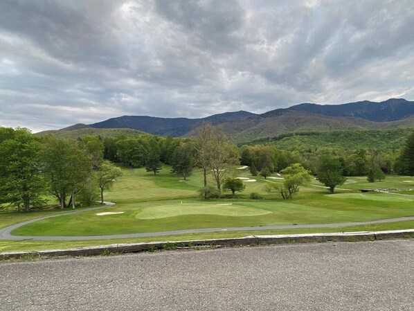 A golf course with a road in the foreground, trees, and mountains in the background. - Bearadise Mtn Cabin~Hot Tub+Fire Pit, Grill & WiFi (Burnsville)
