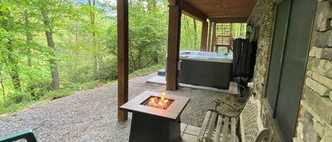 Un patio al aire libre con un pozo de fuego cuadrado, asientos y un muro de piedra.