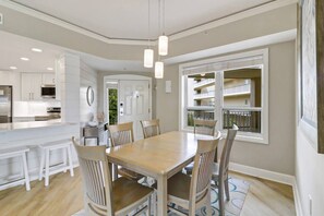 A modern kitchen with white cabinetry, a central island, and a dining area with a wooden table and chairs.