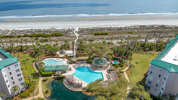Een resort met meerdere zwembaden, uitzicht op het strand en een strandgedeelte.