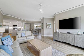 A modern living room with a flat-screen TV, a wooden coffee table, and a sofa with patterned cushions.