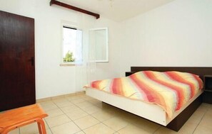 Cozy retreat with a single bed, wooden door, and a window with white curtains.
