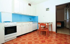 Compact kitchen with stove, sink, and table, featuring a geometric tile floor and blue backsplash.