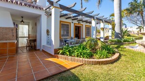 A covered patio with a dining area, a brick wall, and a small garden with plants and a fountain. - Villa Jardin de Mari by Solset (Málaga)