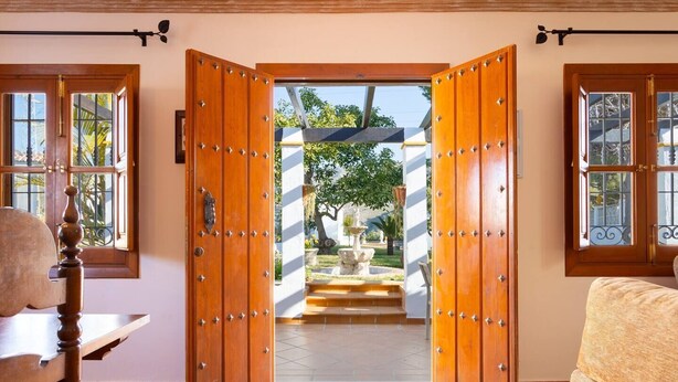 A room with a large wooden door leading to an outdoor area with a fountain and steps. - Villa Jardin de Mari by Solset (Málaga)