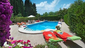 A swimming pool with lounge chairs and sunbeds, surrounded by greenery and flowers. - Villa Rotger, Comfortable and traditional at 800m. from Pollensa (Pollença)