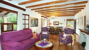 A spacious living room with a purple sofa, patterned armchairs, a wooden coffee table, and a dining area in the background. - Villa Rotger, Comfortable and traditional at 800m. from Pollensa (Pollença)