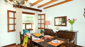 A dining room with a wooden table set for four, a chandelier, and a view of the outdoors. - Villa Rotger, Comfortable and traditional at 800m. from Pollensa (Pollença)