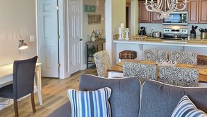 A living room with a gray sofa, patterned cushions, and a dining area with patterned chairs. - TOP RATED / HUGE Balcony Beachfront 3 bed / 3 bath! (Panama City Beach)