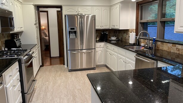 A modern kitchen with stainless steel appliances, white cabinetry, and a black granite countertop. - Family Retreat on Eden Isle Sleeps 12+ with 2 golf carts 4500 sq. ft.  (Heber Springs)