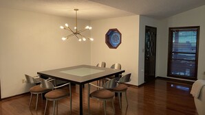 A dining area with a rectangular table, six chairs, a modern chandelier, and a decorative wall piece. - Family Retreat on Eden Isle Sleeps 12+ with 2 golf carts 4500 sq. ft.  (Heber Springs)