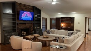 A modern living room with a fireplace, a large TV, and a cozy seating area. - Family Retreat on Eden Isle Sleeps 12+ with 2 golf carts 4500 sq. ft.  (Heber Springs)