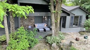 A modern house with a stone facade, a covered patio with outdoor furniture, and a large window. - Family Retreat on Eden Isle Sleeps 12+ with 2 golf carts 4500 sq. ft.  (Heber Springs)