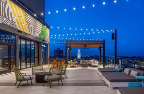 An outdoor terrace with seating, string lights, and a view of the city skyline. - Hilton Garden Inn Austin University Capitol District (Austin)