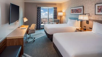 Une chambre d’hôtel avec deux lits, un bureau, une chaise, une télévision et une vue sur la ville.