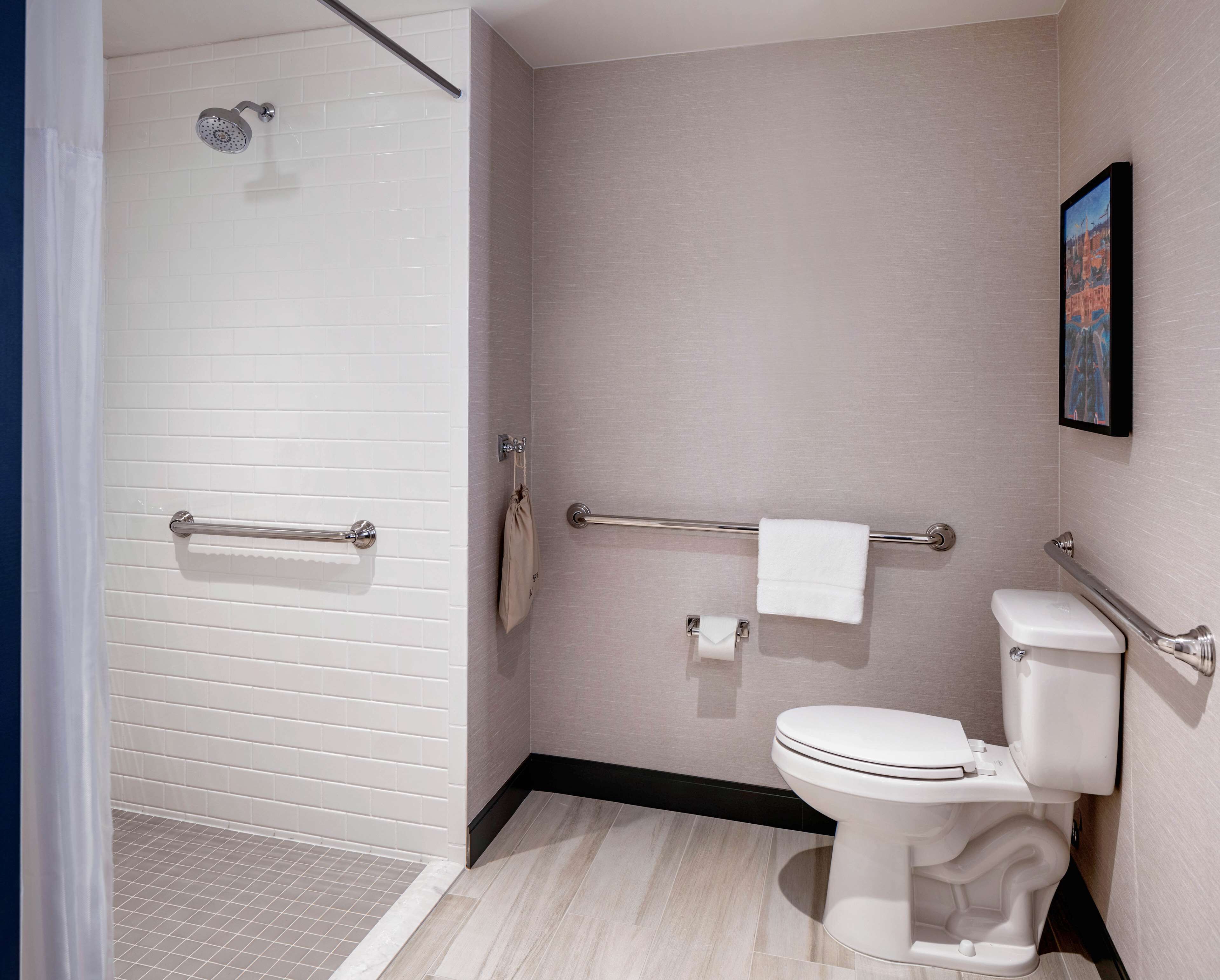 A modern bathroom with a shower, toilet, and towel rack.