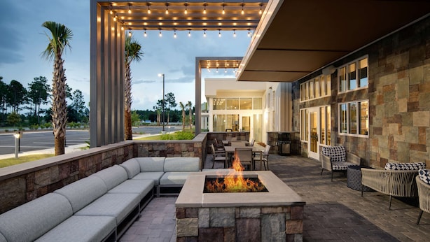 An outdoor patio with a fire pit, seating, and a covered area with string lights.