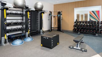 A gym with weightlifting equipment, kettlebells, and dumbbells.