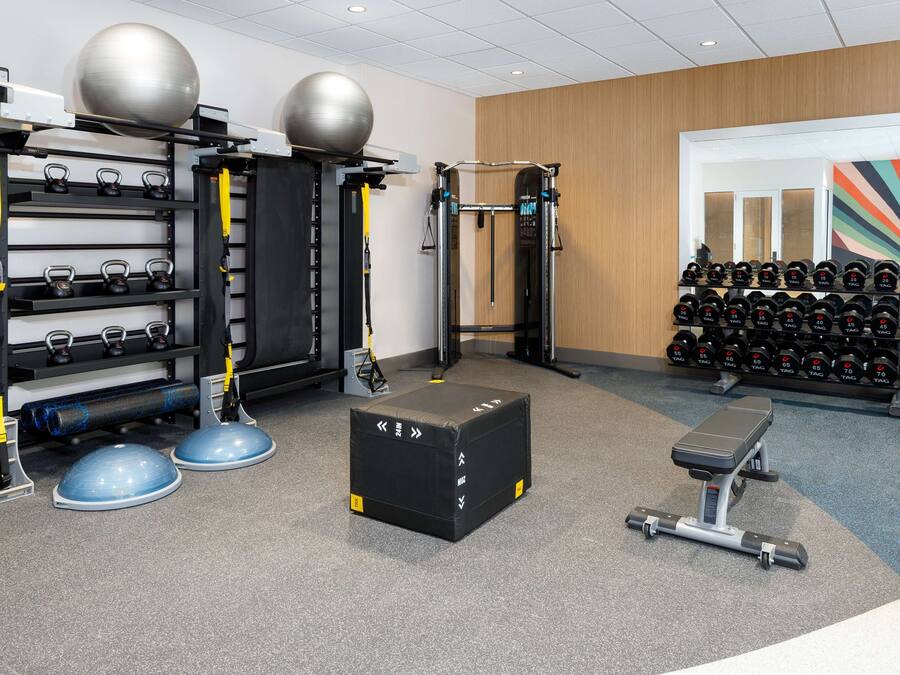 A gym with weightlifting equipment, kettlebells, and dumbbells.
