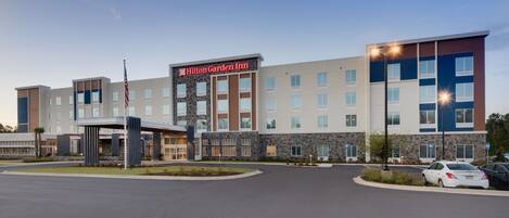 A modern hotel with a prominent sign, multiple floors, and a parking area.