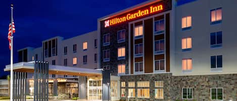 Un hotel Hilton Garden Inn con diseño moderno, que presenta fachada de piedra y numerosas ventanas.