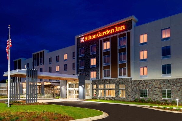 A Hilton Garden Inn hotel with a modern design, featuring a stone facade and multiple windows.