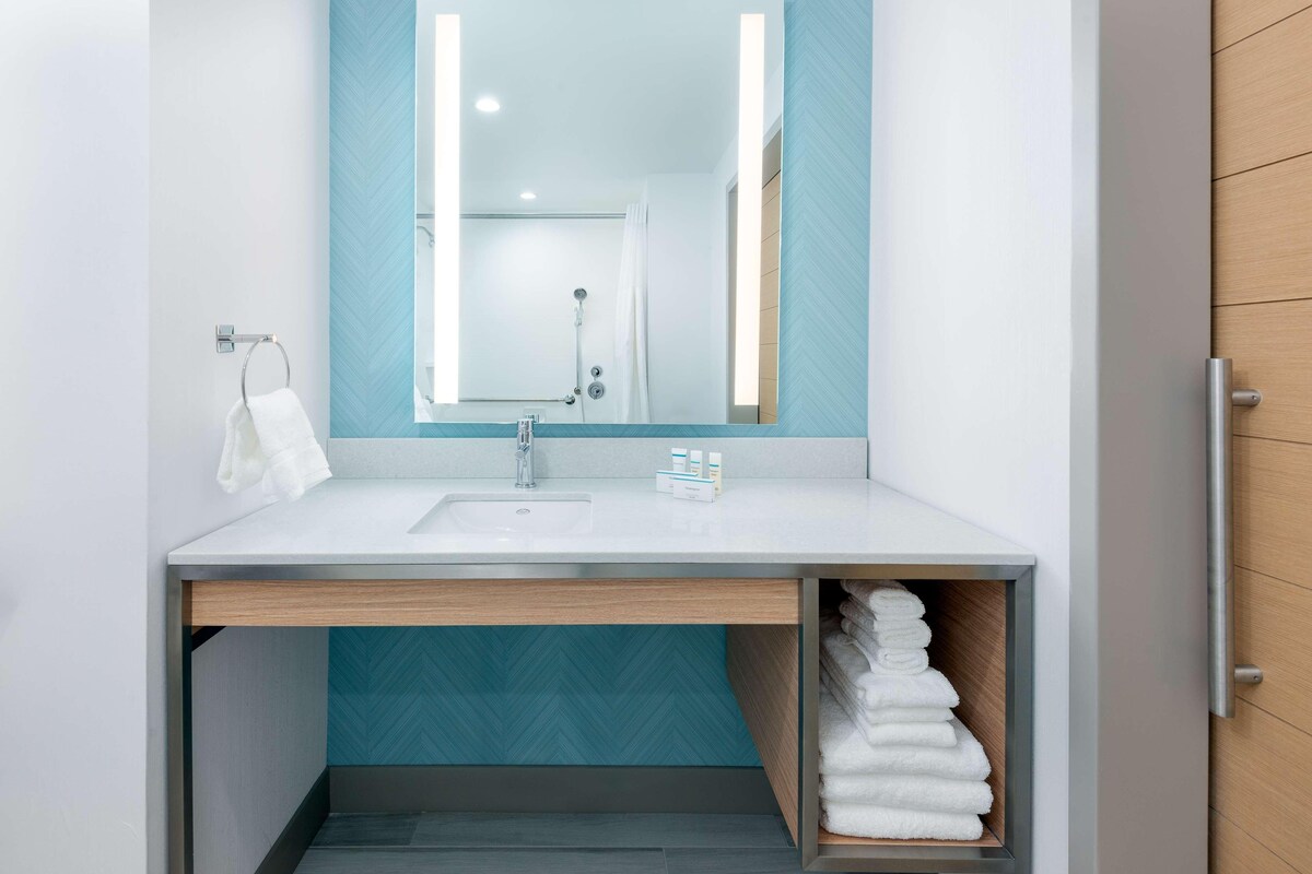 A modern bathroom with a white sink, a mirror, and a towel rack.